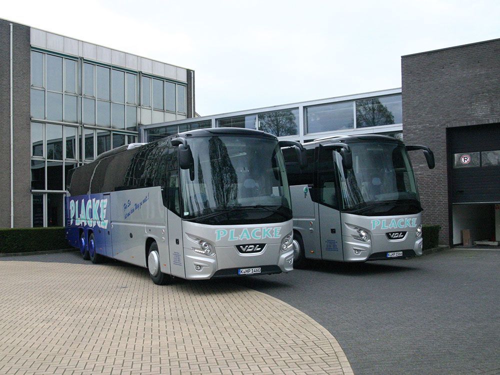 Zwei Busse stehen vor einem Gebäude und einer von ihnen sagt Pilot