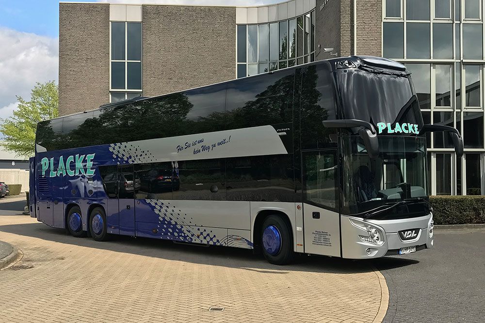 Ein Bus mit dem Wort „Place“ auf der Seite steht vor einem Gebäude
