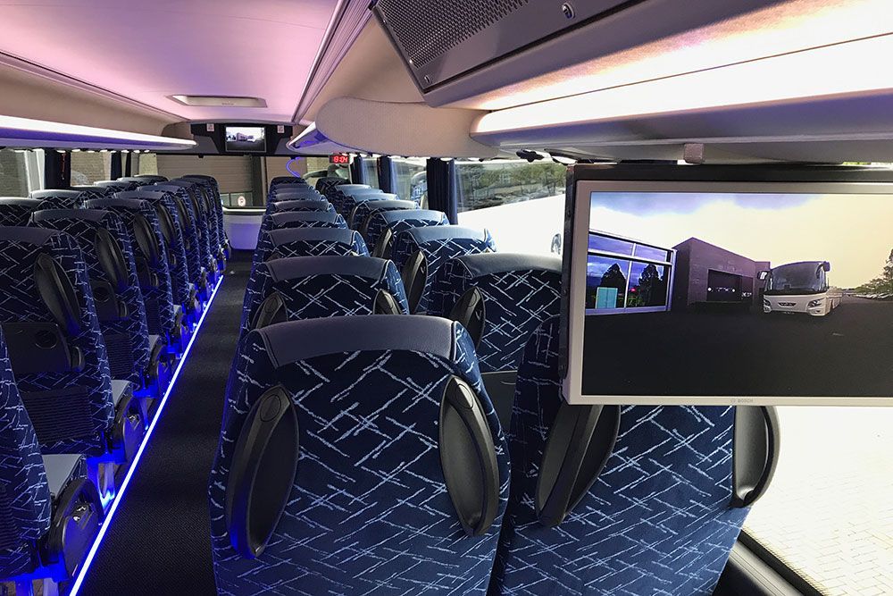 Das Innere eines Busses mit blauen Sitzen und einem Monitor darüber
