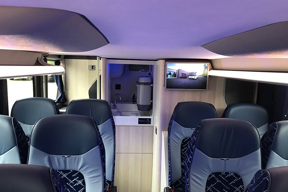 Das Innere eines Busses mit blauen Sitzen und einem Fernseher