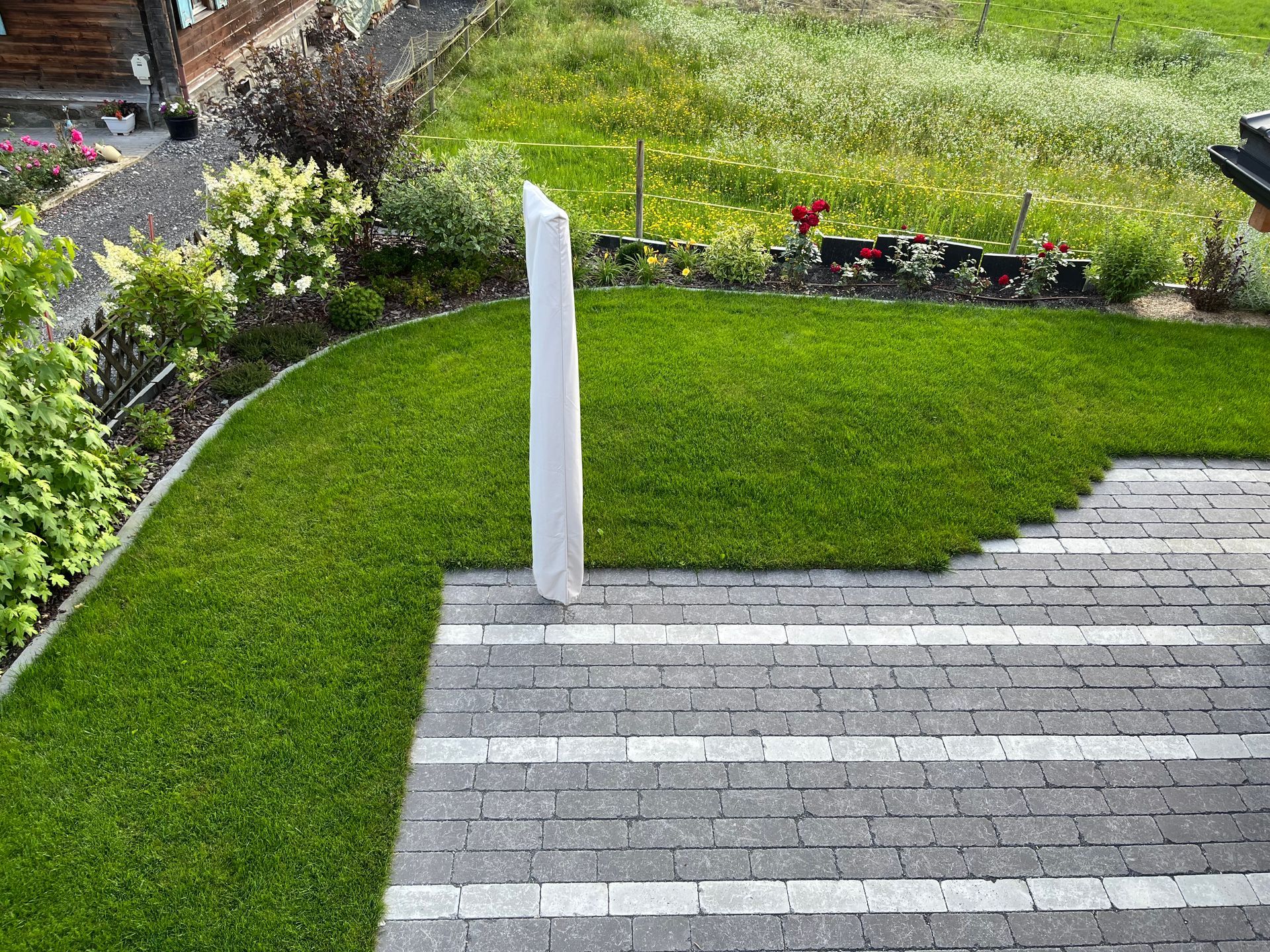 Une cour arrière avec une clôture en bois, un patio et un parasol.