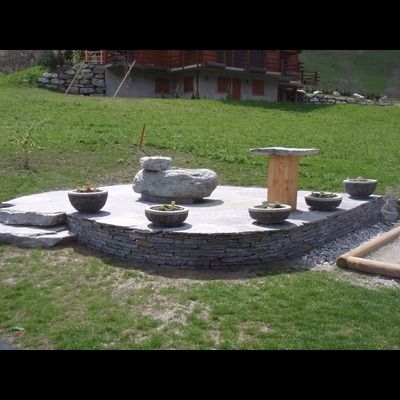 Un patio en pierre avec une table et des plantes en pot devant une maison.