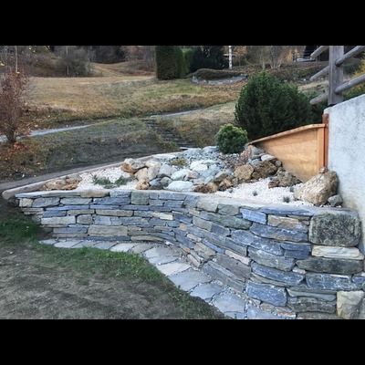Un mur de pierre avec un chemin qui y mène dans un jardin.