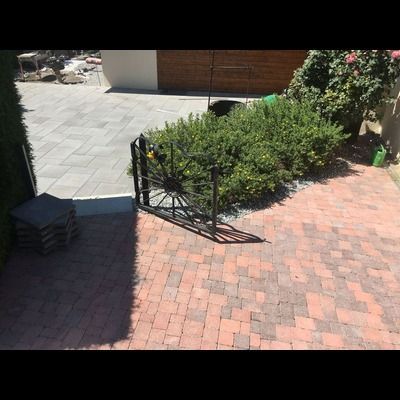 Une allée en briques avec une roue de chariot au milieu.