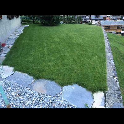 Une pelouse verte luxuriante est entourée de rochers et de gravier.