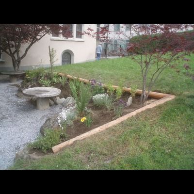 Un jardin avec des fleurs et un banc devant un immeuble