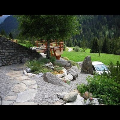 Une voiture est garée dans une zone rocheuse devant un mur de pierre.