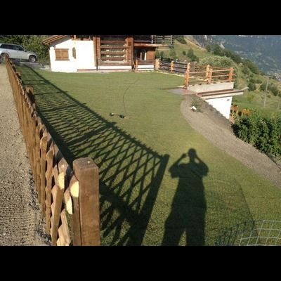 L'ombre d'une personne est projetée sur l'herbe près d'une clôture en bois