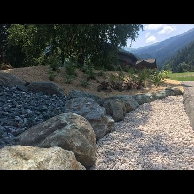 Une rangée de rochers assis à côté d'un tas de gravier avec des montagnes en arrière-plan.