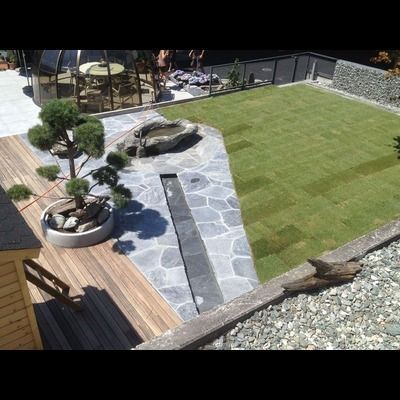 Une vue aérienne d'une cour arrière avec une terrasse en bois et une pelouse verte luxuriante.