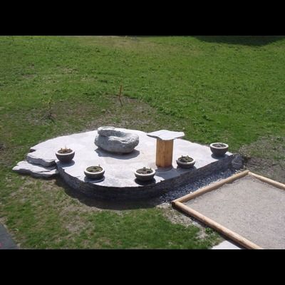 Une sculpture en pierre au milieu d'un champ herbeux