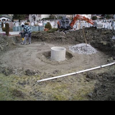 Un homme creuse un trou dans le sol à côté d'un grand anneau de béton.