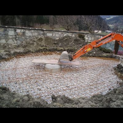 Une grande excavatrice orange creuse un trou dans le sol.