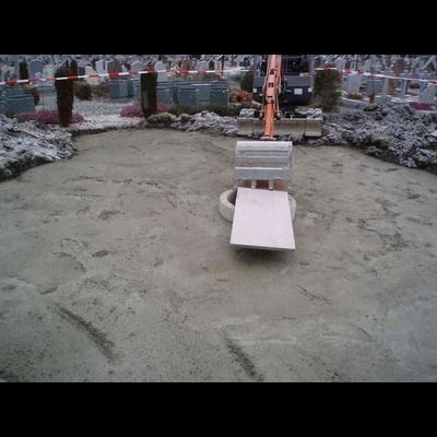 Une excavatrice travaille dans un cimetière entouré de tombes