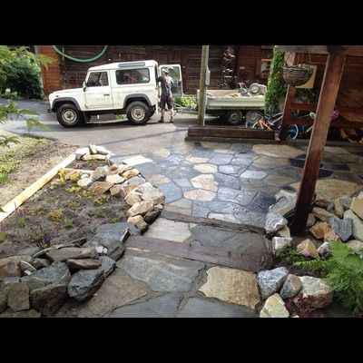 Une jeep blanche est garée dans une allée à côté d'un passage en pierre.