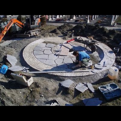 Un homme est agenouillé dans la terre et travaille sur un cercle de pierres