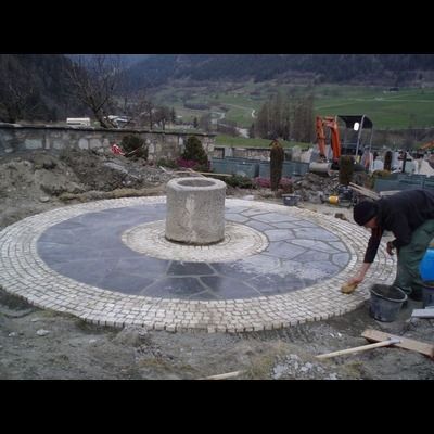 Un homme travaille sur un patio circulaire avec un puits au milieu.