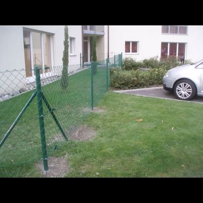 Une voiture est garée devant une clôture grillagée.