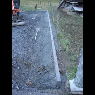 Une pelle est posée sur un tas de terre à côté d'une clôture.