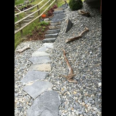 Une allée en pierre menant à une clôture en bois entourée de rochers.
