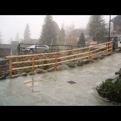 Une clôture en bois est entourée de rochers et d'arbres un jour de pluie.