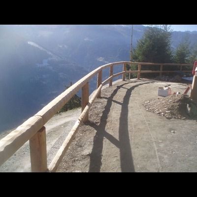 Une clôture en bois entoure une falaise surplombant un lac.