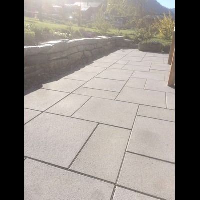 Un patio avec un mur de pierre et une montagne en arrière-plan.