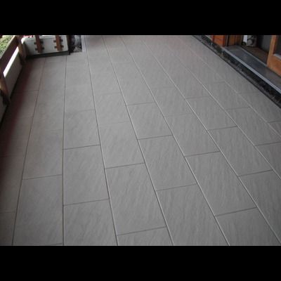 Un sol carrelé sur un balcon avec une balustrade en bois