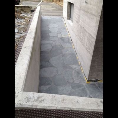 Une passerelle en pierre est en cours de construction à côté d'un mur en béton.