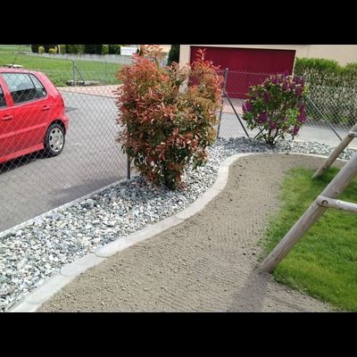 Une voiture rouge est garée devant une clôture grillagée