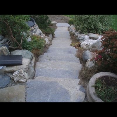 Un ensemble d'escaliers en pierre menant à une maison entourée de rochers.