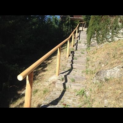 Un escalier avec une rampe en bois qui monte une colline.