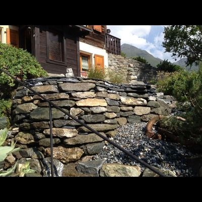 Un mur de pierre avec des escaliers menant à une maison