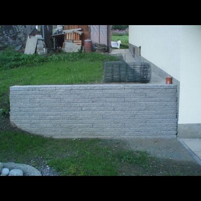 Un mur de briques est devant un bâtiment blanc