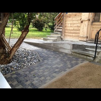 Une allée en briques avec des escaliers menant à un bâtiment en bois.