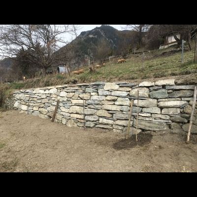 Un mur de pierre est en train d'être construit au sommet d'une colline de terre.