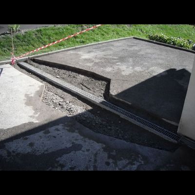 Un système de drainage est en cours d'installation sur le côté d'une allée.