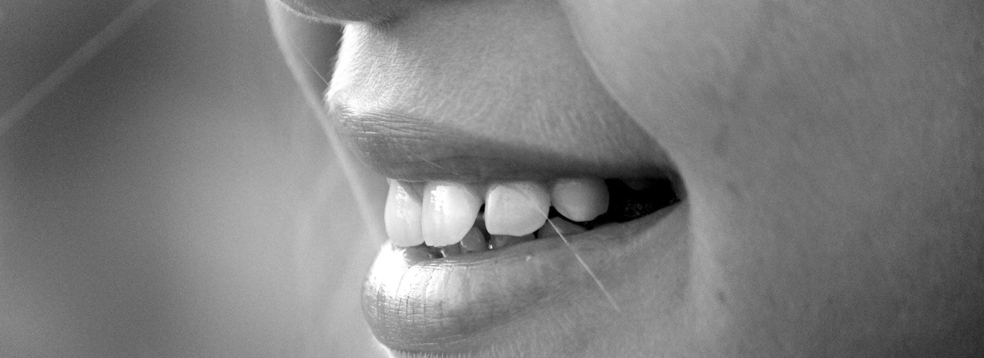 Un primer plano de la boca de una mujer con sus dientes visibles en una fotografía en blanco y negro.