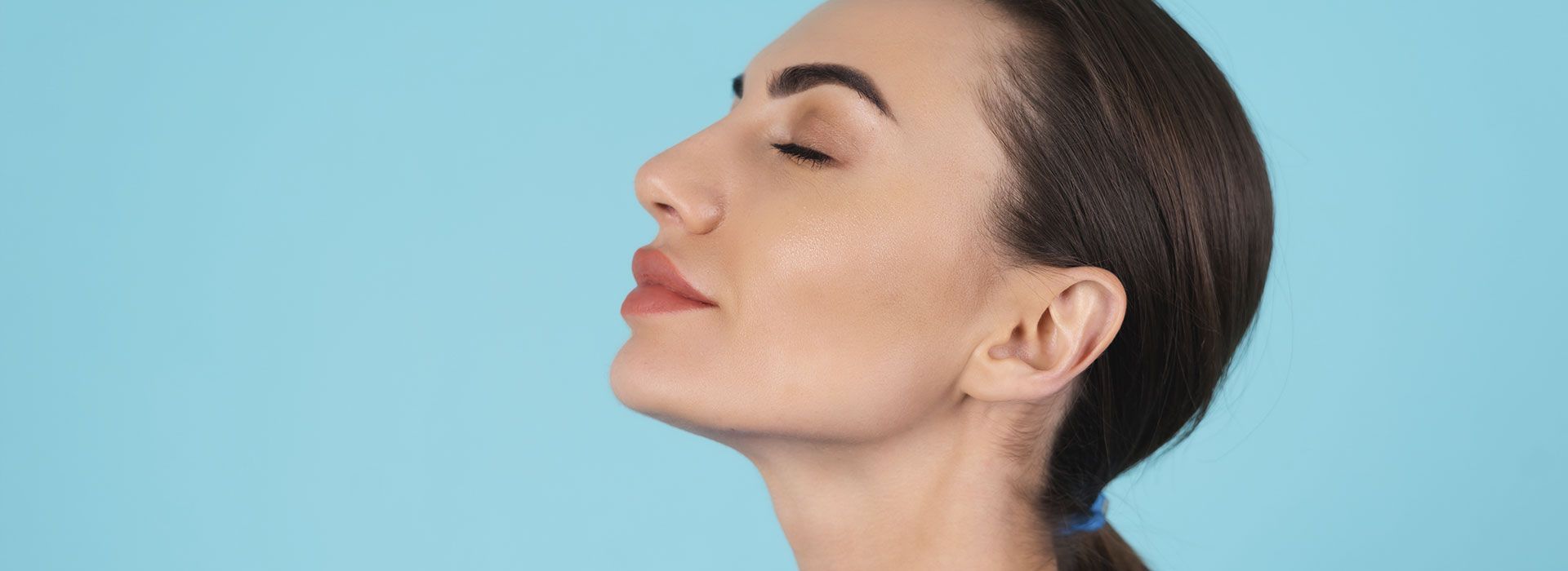 Un primer plano del rostro de una mujer con los ojos cerrados sobre un fondo azul.