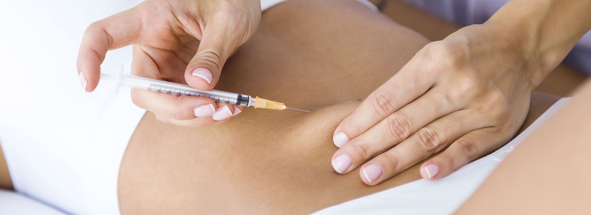 Una mujer recibe una inyección en el estómago.