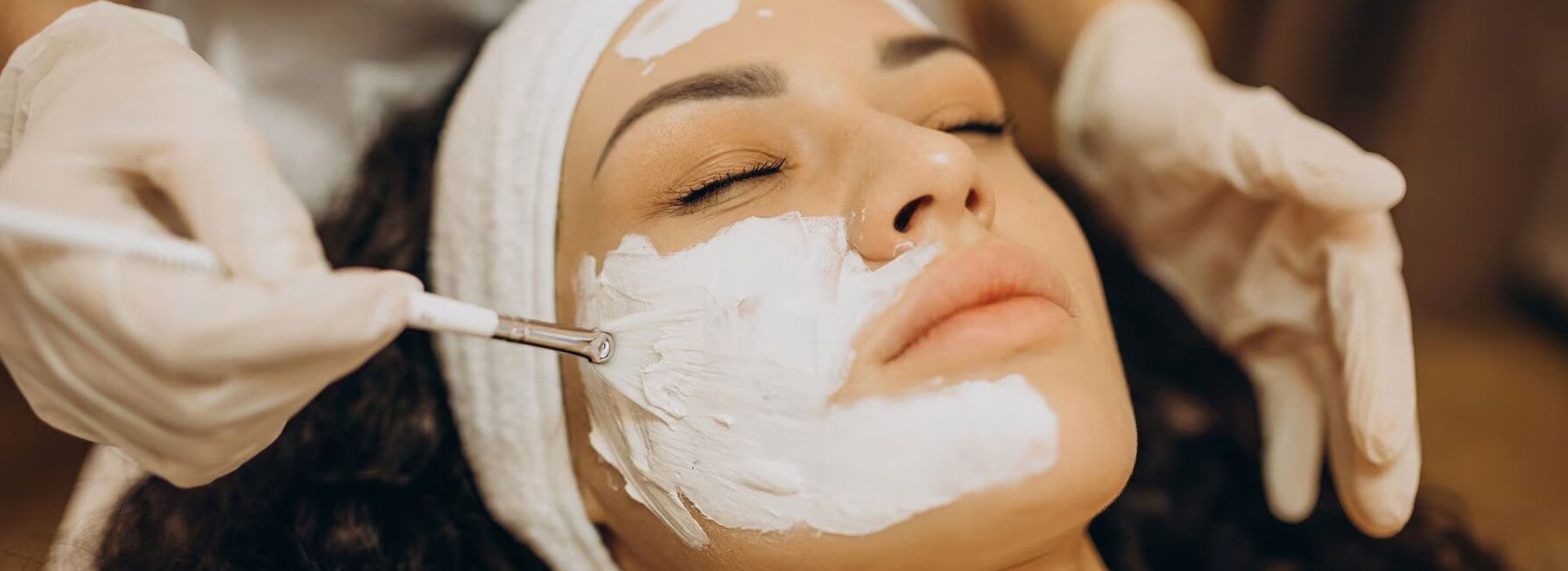 Una mujer se pone una máscara blanca en la cara.