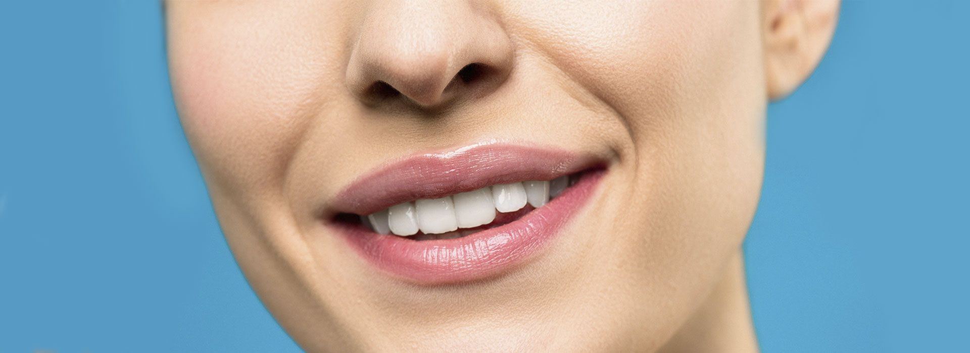 Un primer plano del rostro de una mujer con dientes blancos y labios rosados.