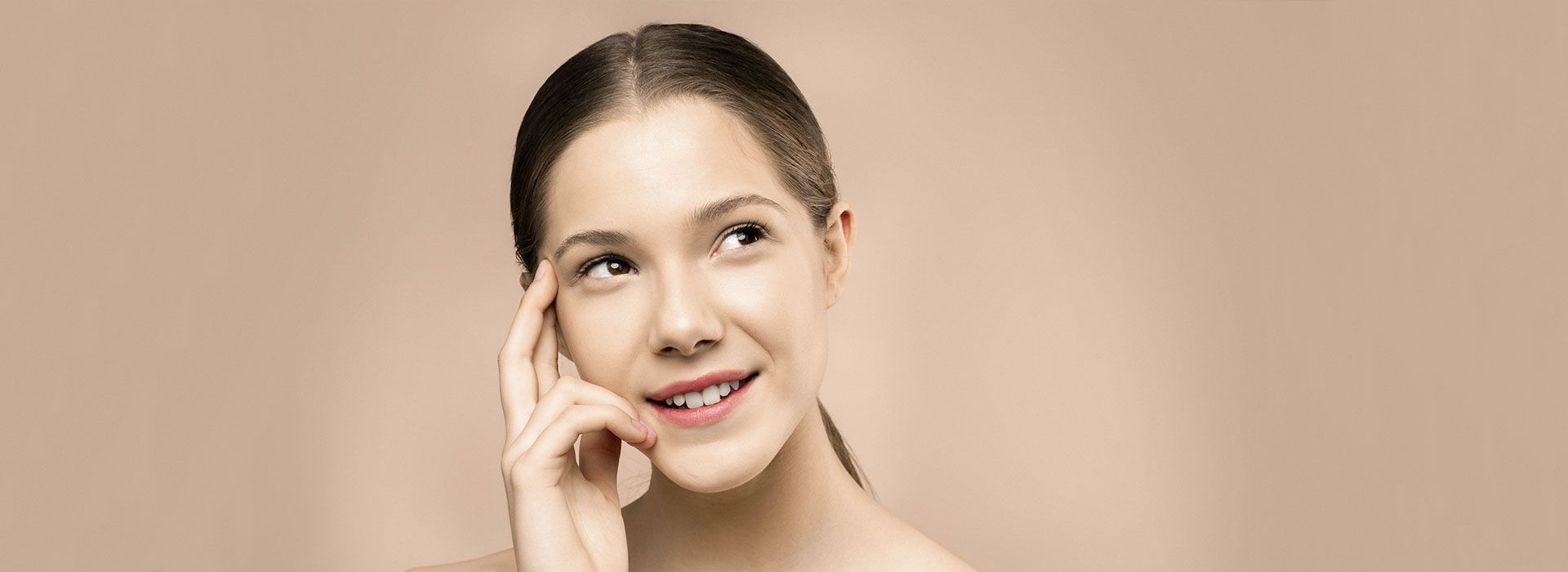 Una mujer con aparatos dentales sonríe y se toca la cara.