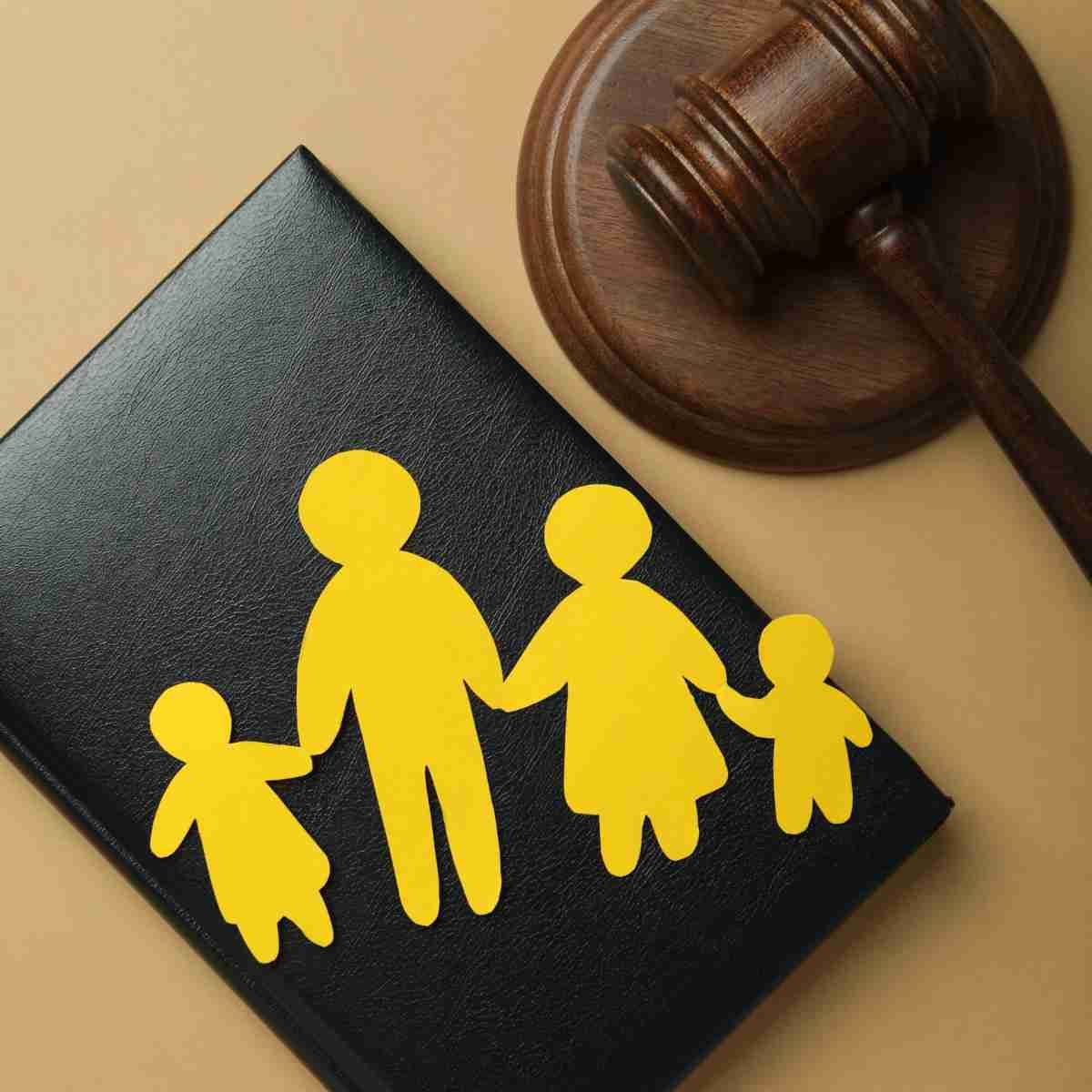 Un mazo de juez está junto a un libro negro con siluetas amarillas de una familia.