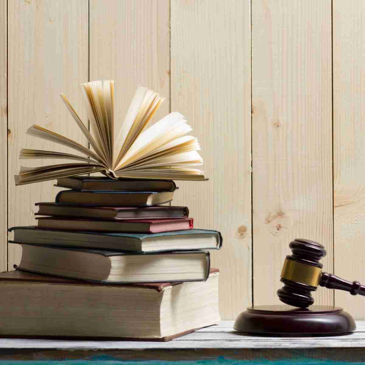 Una pila de libros y un mazo de juez sobre una mesa de madera.