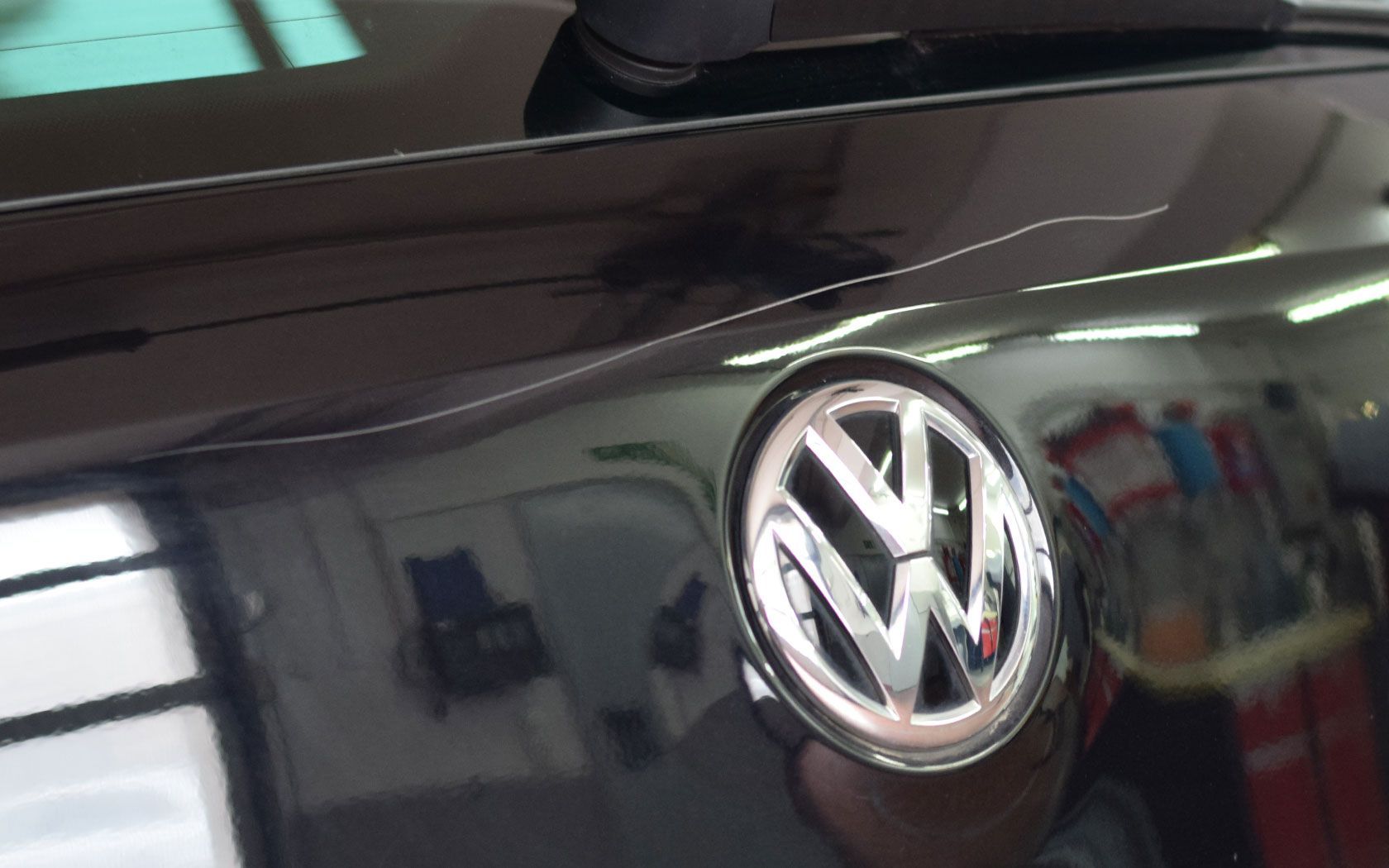 Nahaufnahme einer roten Motorhaube und eines schwarzen Kühlergrills mit Wabengitterdetail.