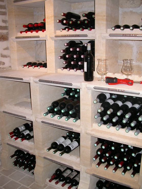 Étagères en pierre blanche et pleines de bouteilles dans une cave à vin