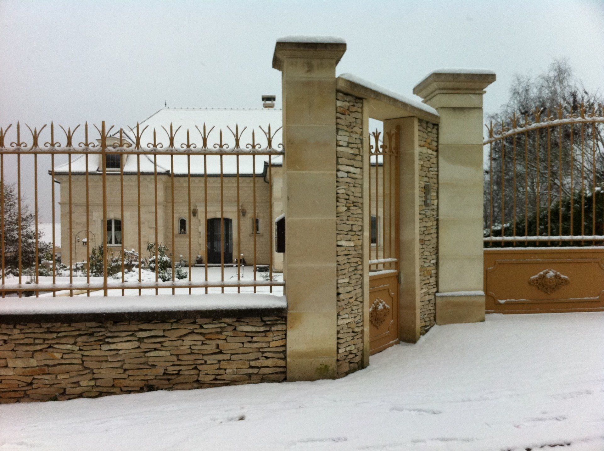 Magnifique portail en pierre et en fer forgé sous la neige