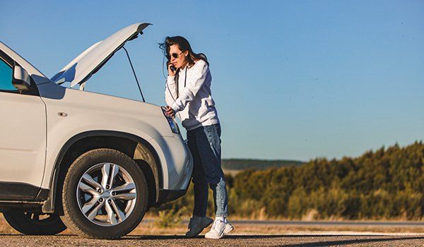 Une femme au téléphone devant son véhicule