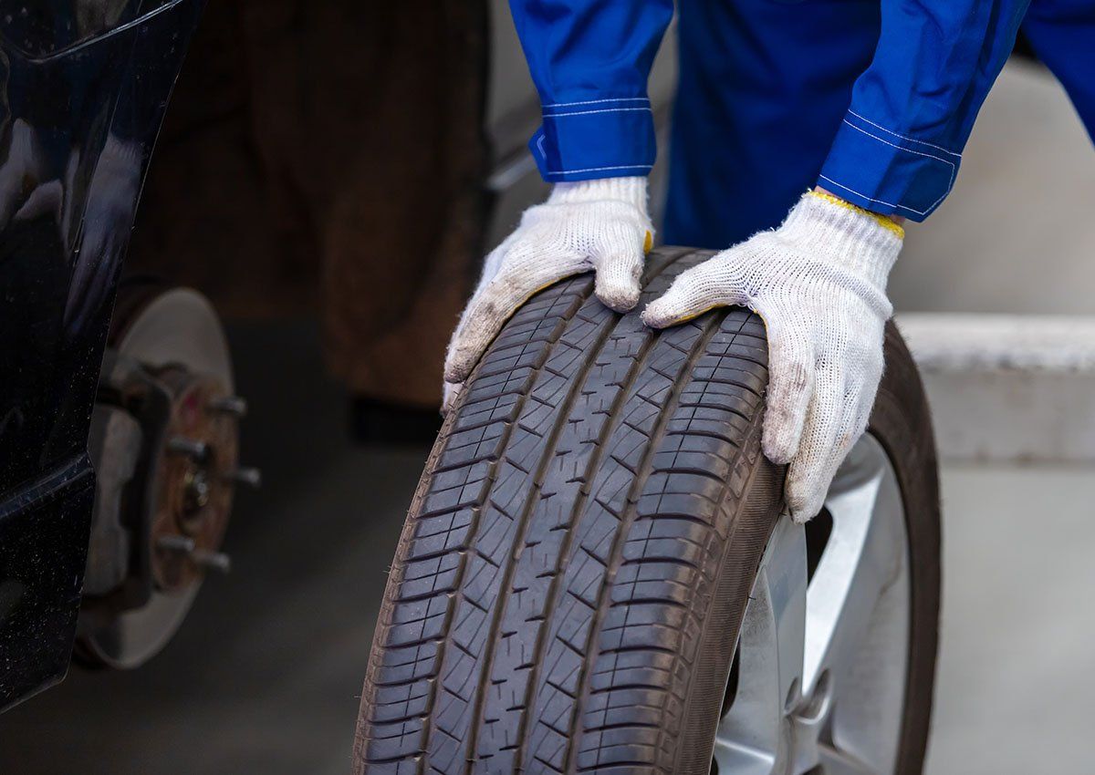 Un garagiste tient en main un pneu neuf
